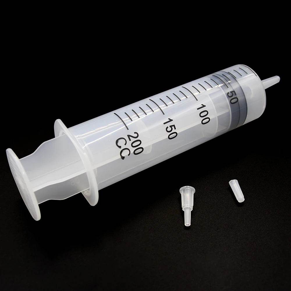 Large plastic syringe with tube and two small detachable tips on black background