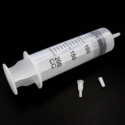 Large plastic syringe with tube and two small detachable tips on black background